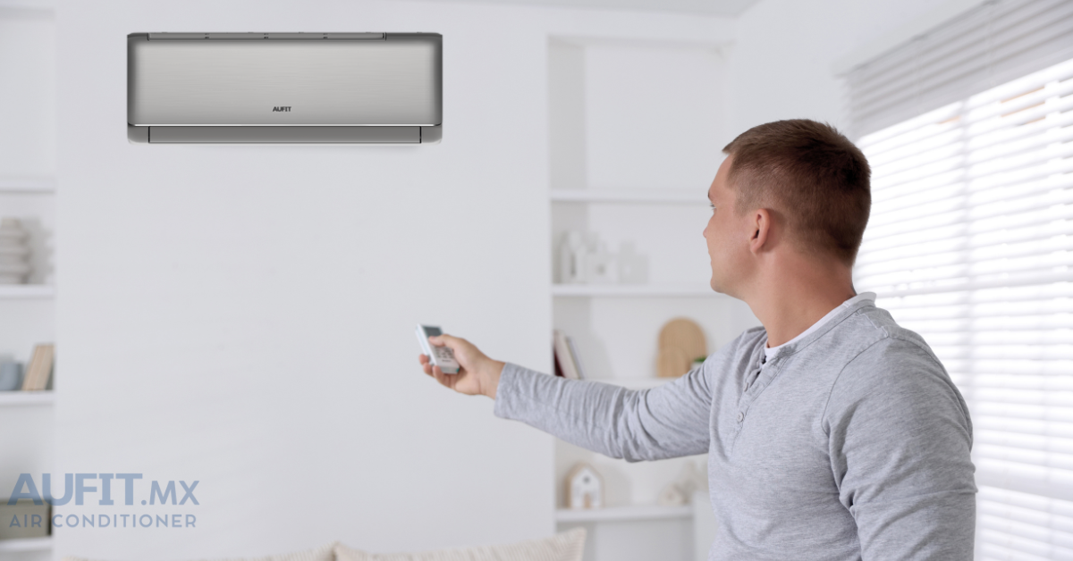 aire acondicionado beneficios aufit ahorro Hombre usando un control remoto para ajustar el aire acondicionado en una sala moderna.
